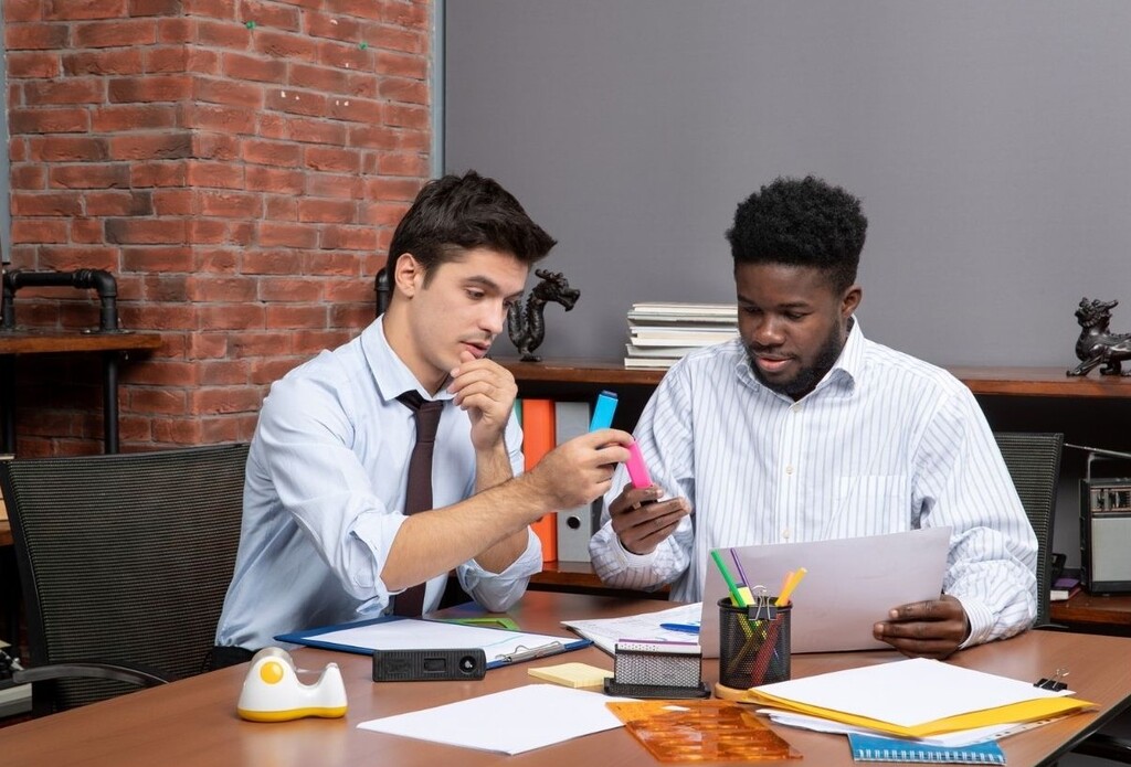 Two professionals reviewing documents and discussing strategy highlighting sales marketing alignment challenges in B2B teams